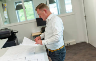 Medewerker RENDO achter bureau met plattegronden