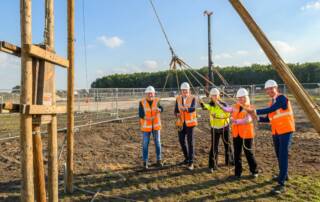 5 personen met veiligheidshelm op openen vrolijk de bouw van Hoogeveen Riegmeer