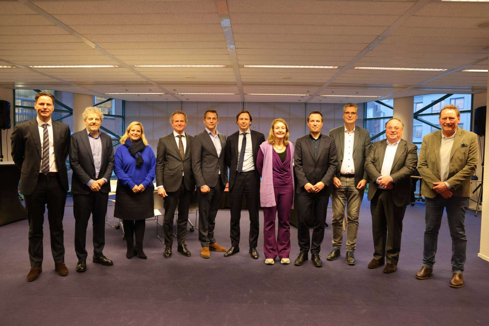 Groepsfoto van 11 personen op een rij.